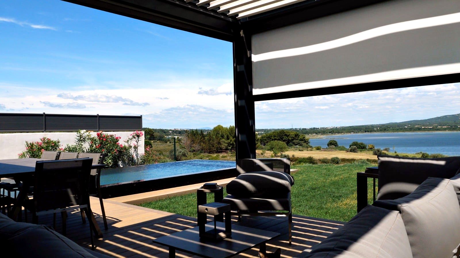 Vu d'une terrasse sur l'étang de thau avec en premier plan une pergola bioclimatique et un store vertical pour se protéger du soleil